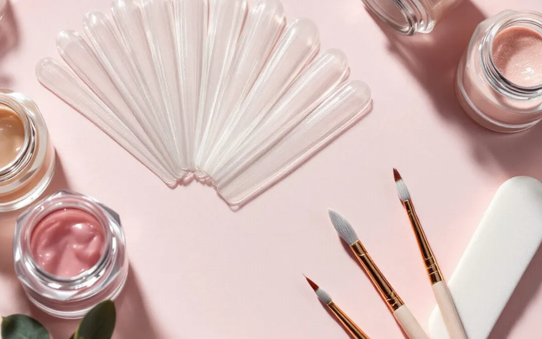 Capsules transparentes, pots de gel et pinceaux sur fond rose